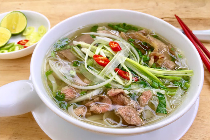 Steaming bowl of Vietnamese pho noodle soup with herbs in Hanoi