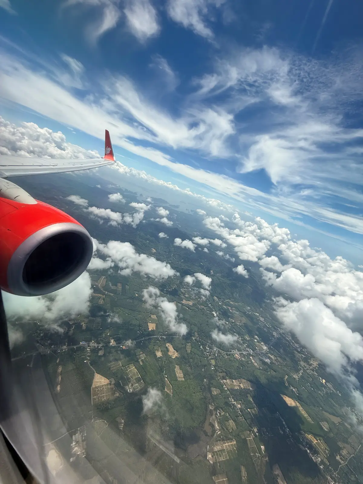 Island coastline and clouds viewed from plane window approaching Phuket