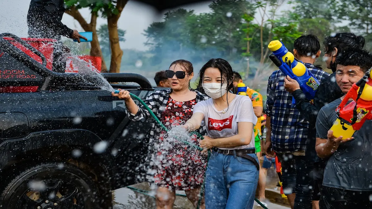 Locals and tourists smiling and spraying water during Songkran 2025 in Phuket