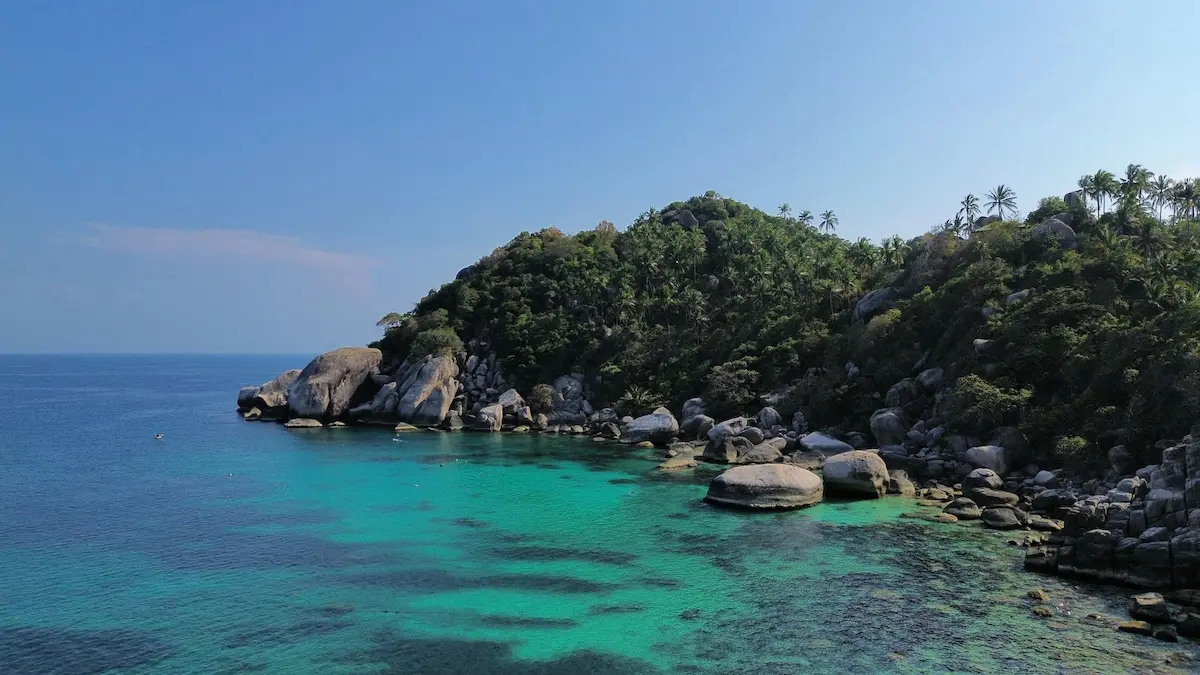 Turquoise water and granite rocks along a forested coastline at Koh Tao island, Thailand