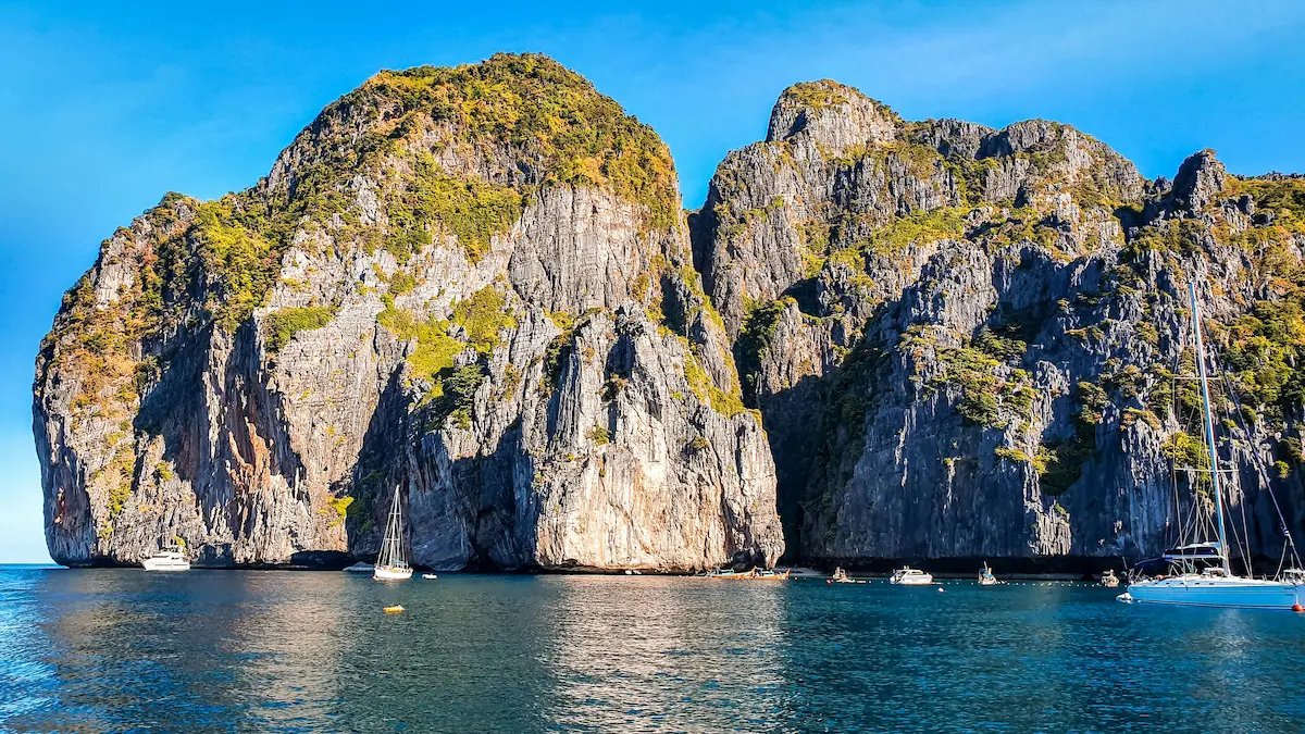 Limestone cliffs and blue water with sailing boats in the Andaman Sea, Thailand.