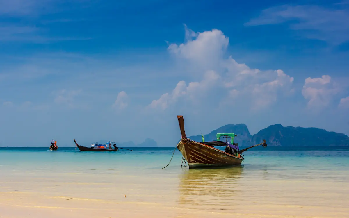 Traditional Thai longtail boats resting on the turquoise waters of Koh Lanta, featured in the Complete Thailand Islands Guide.