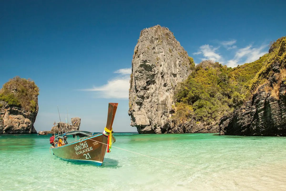 Longtail boat moored in a turquoise bay with limestone cliffs during a phi phi islands tour from Phuket