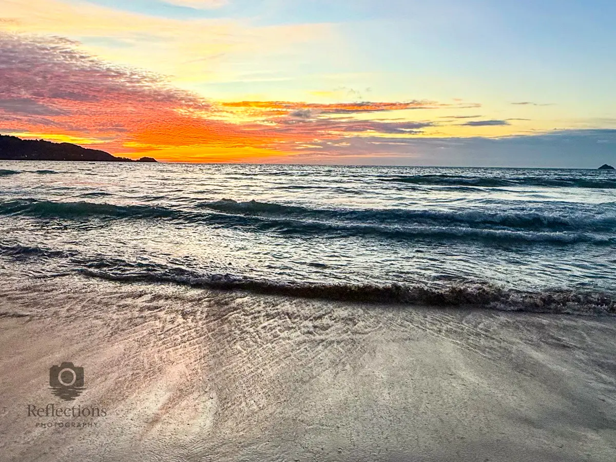 Golden sunset over Patong Beach Phuket with gentle waves and colorful clouds reflecting on wet sand