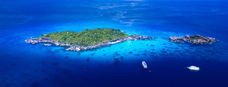 Aerial view of the Similan Islands’ turquoise lagoon with dive boats anchored offshore, featured in the Complete Thailand Islands Guide.