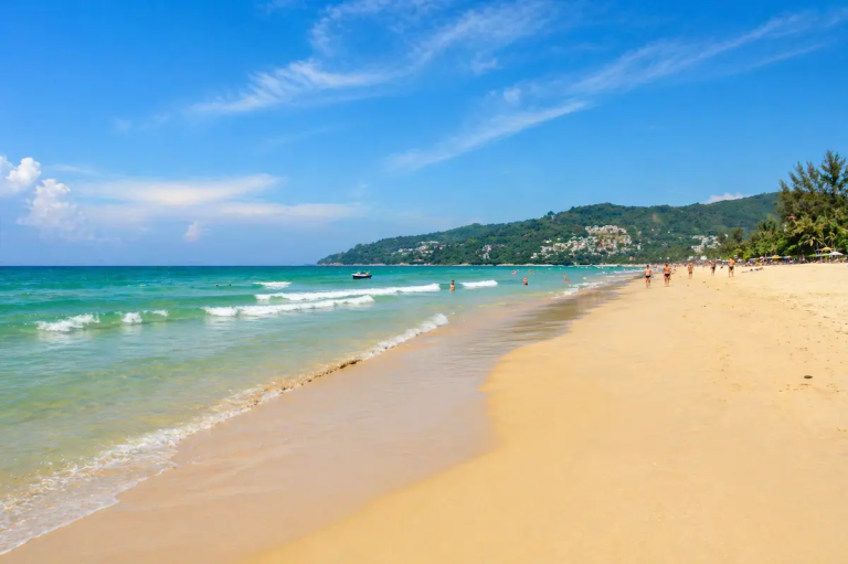 Karon Beach Phuket with a long sandy shoreline, clear water, and a spacious beach atmosphere