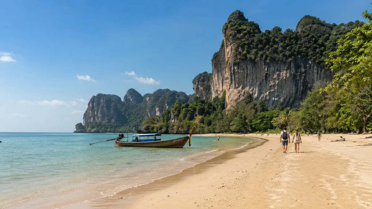 Krabi beach in Thailand with longtail boat, limestone cliffs and calm tropical shoreline for Phuket vs Krabi comparison