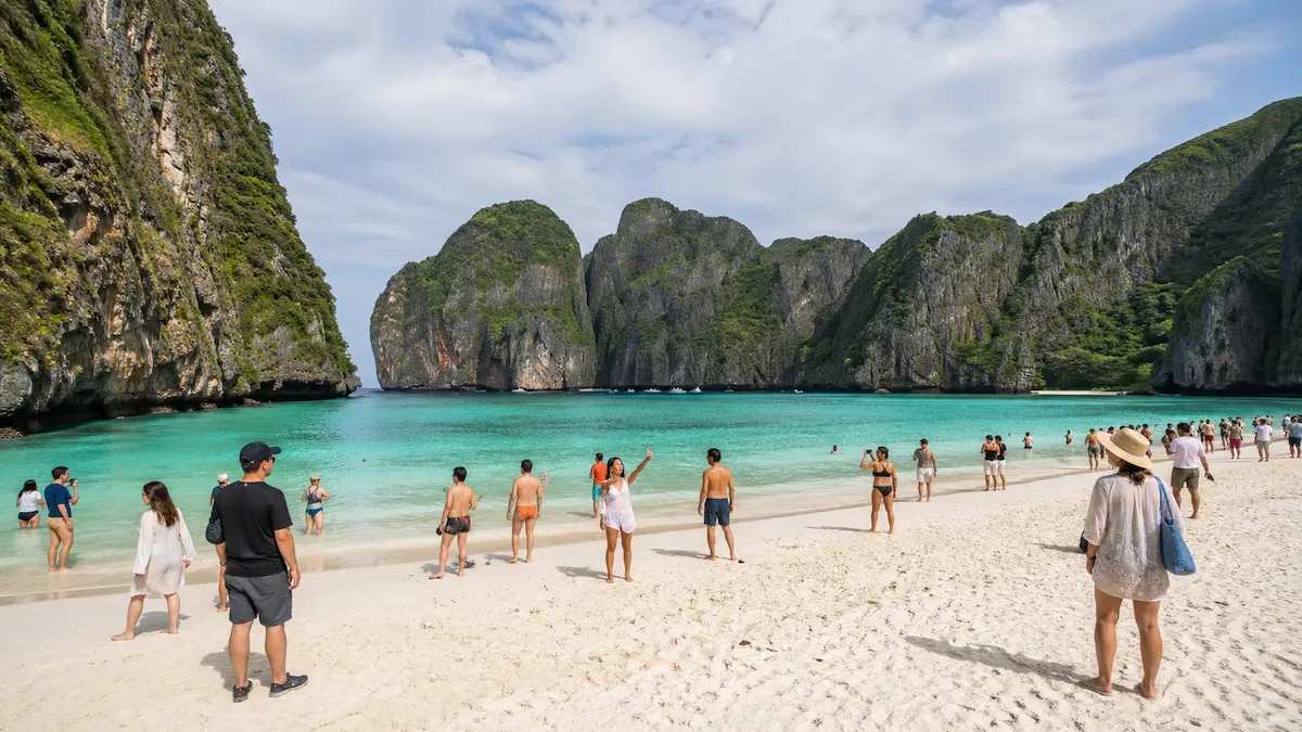 Maya Bay Phi Phi Islands visited on a Phi Phi island tour from Phuket with beach visitors and limestone cliffs
