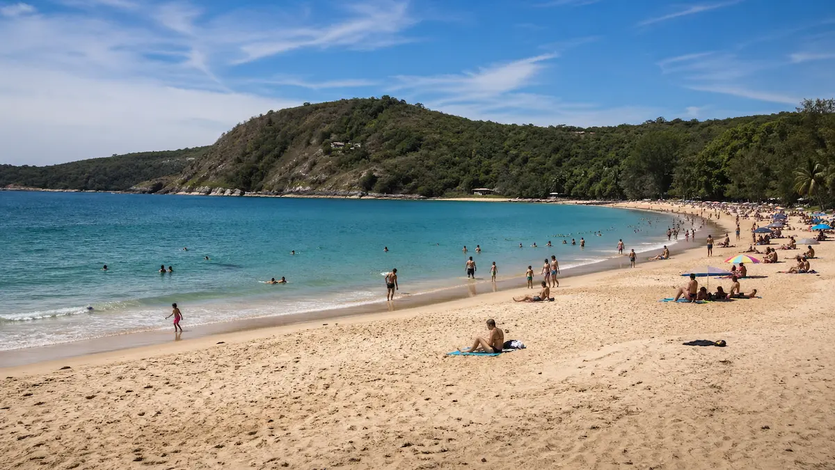 People swimming and relaxing on the sand at Nai Harn Beach Phuket near Rawai