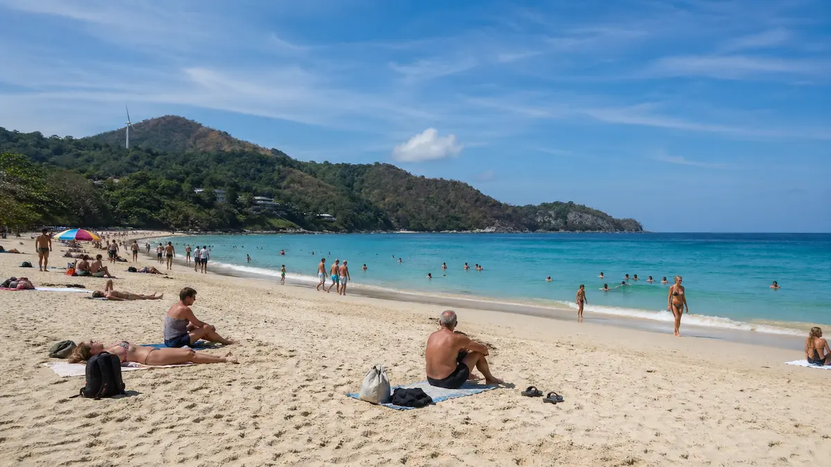 Visitors swimming and relaxing on the sand at Nai Harn Beach Phuket