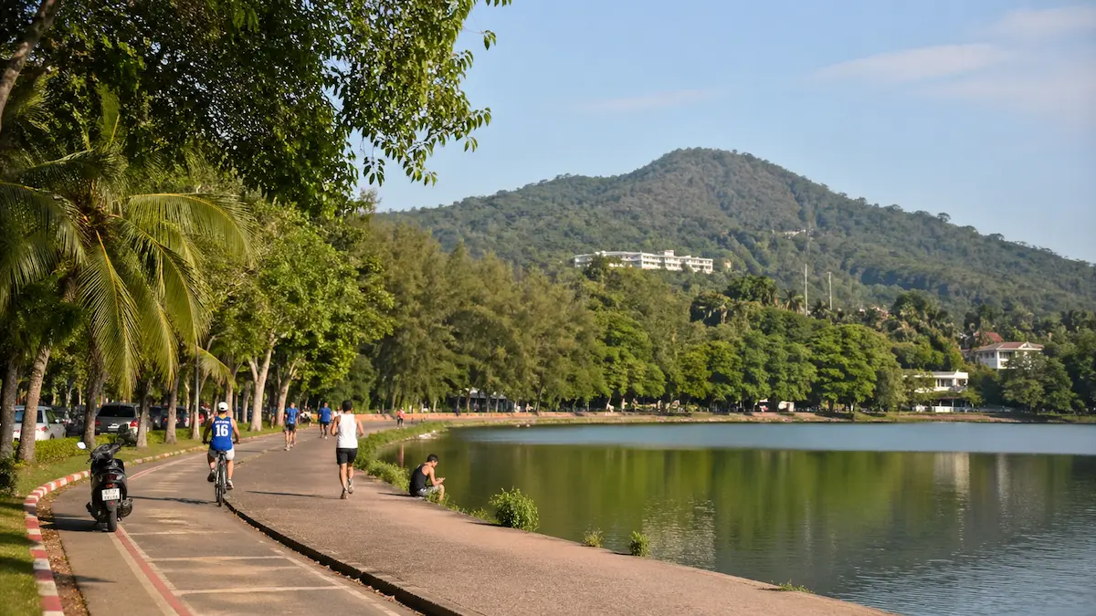 Walking path beside Nai Harn Lake Phuket with tropical trees and hillside backdrop