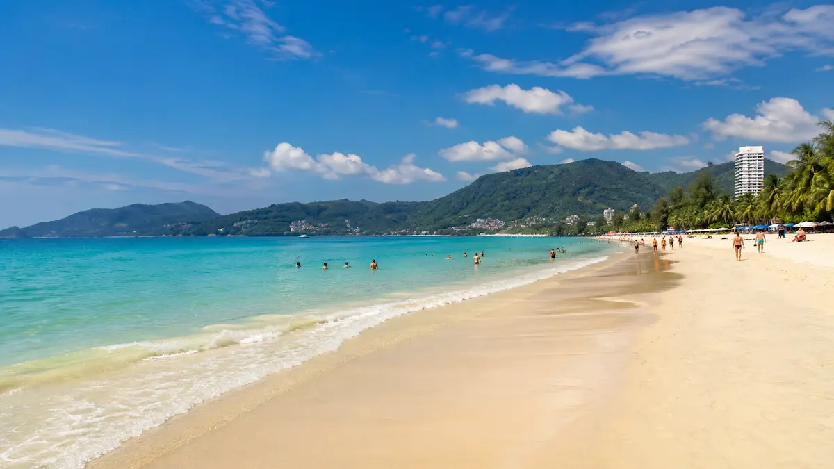 Patong Beach Phuket Thailand showing golden sand turquoise water and visitors enjoying the coastline on a sunny day