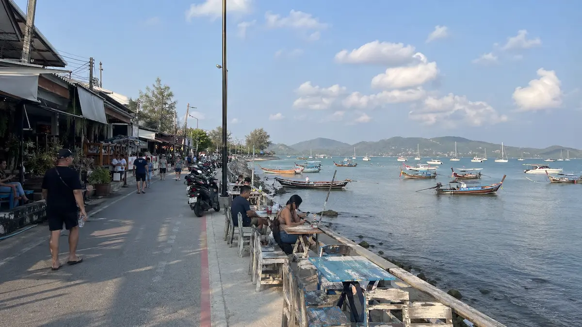 Waterfront road with local restaurants and longtail boats at Rawai Beach Phuket