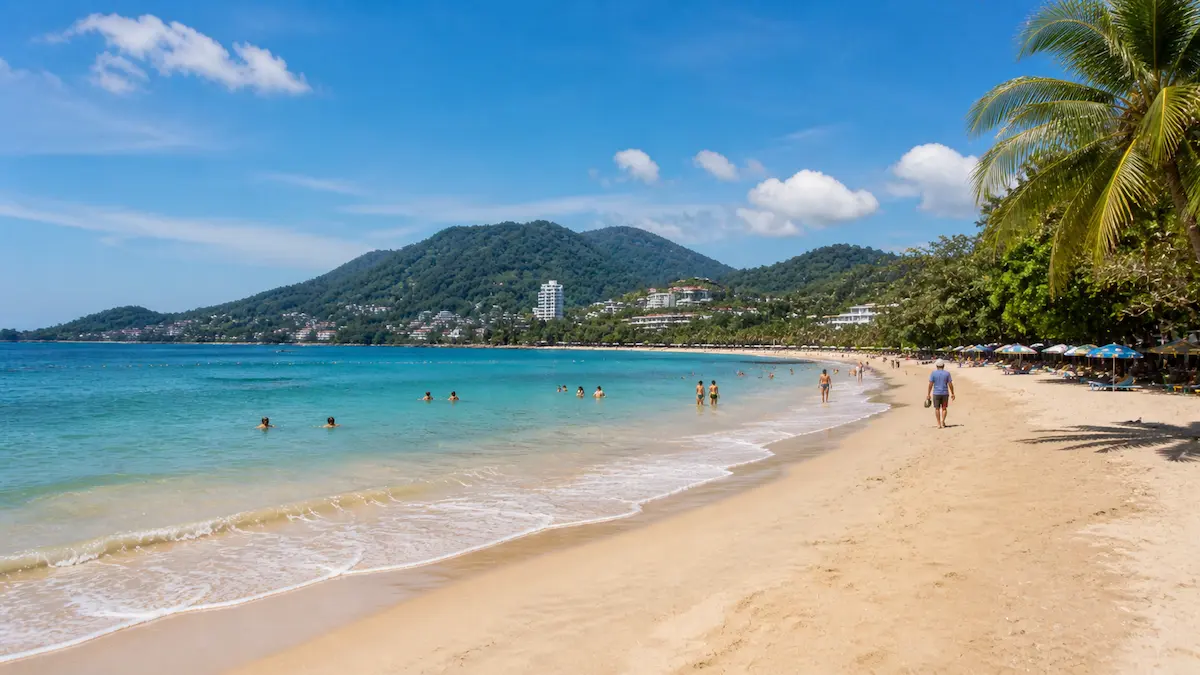 Phuket beach scene with tourists swimming and walking showing a safe and relaxed travel environment