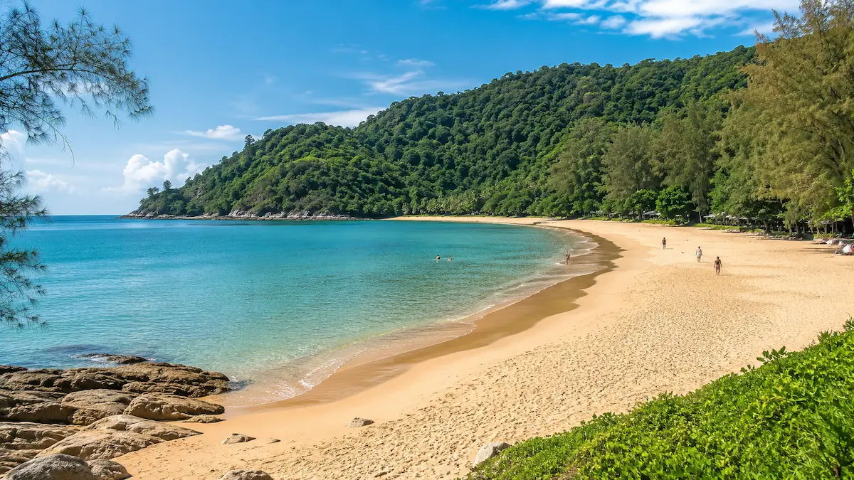 Nai Thon Beach in north Phuket with calm water, golden sand, and green hillside scenery