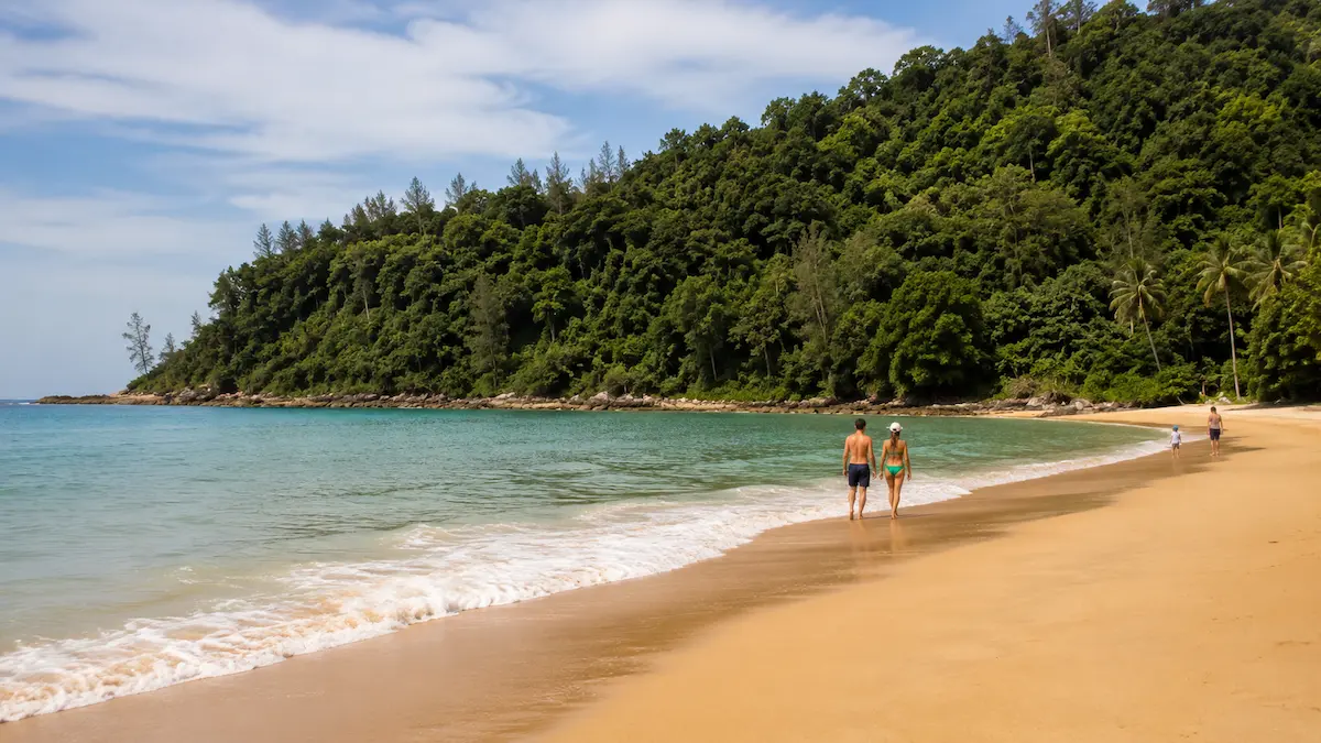 Couple walking along the quiet shoreline at Nai Thon Beach in north Phuket