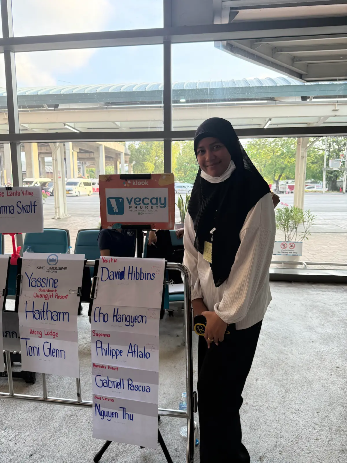 Private transfer driver waiting with passenger name signs at Phuket Airport arrivals