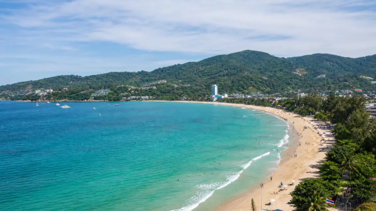 Phuket travel guide coastline view showing turquoise bay, sandy beach and hillside scenery in Thailand