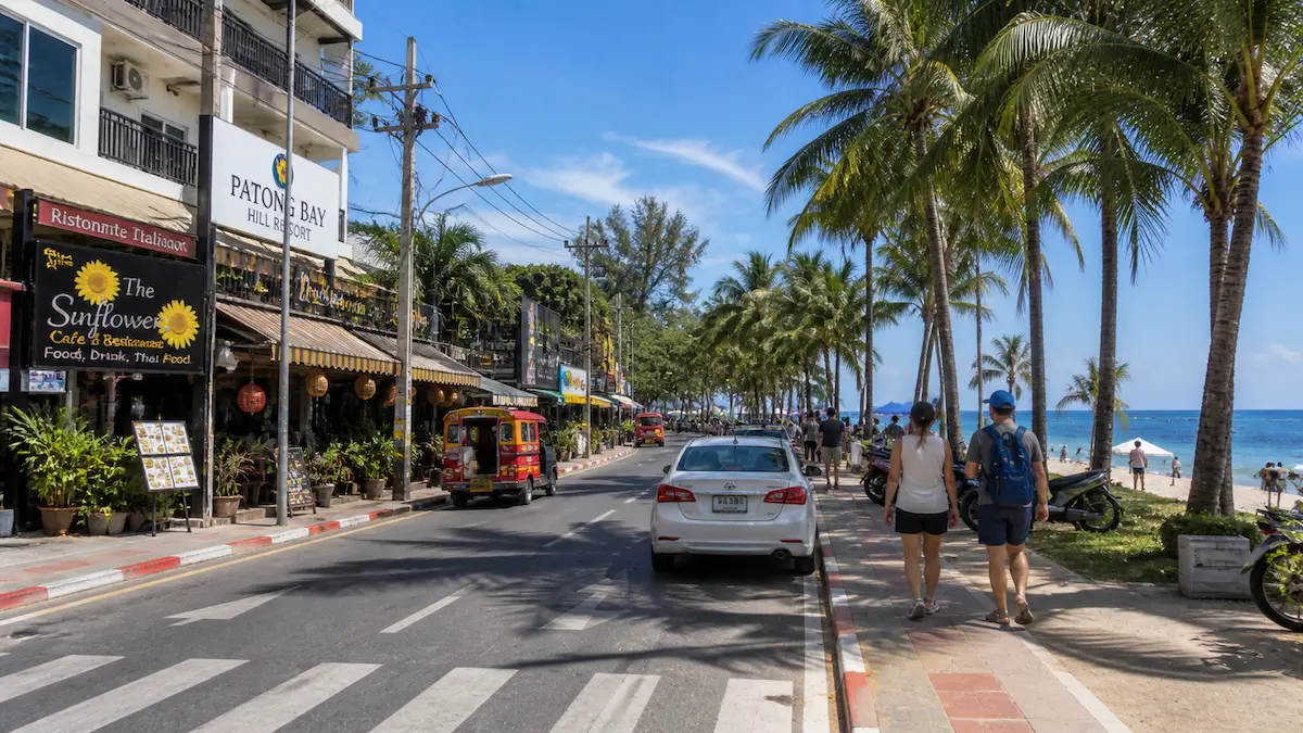 Phuket beach road with tourists walking past hotels and cafes showing practical travel environment