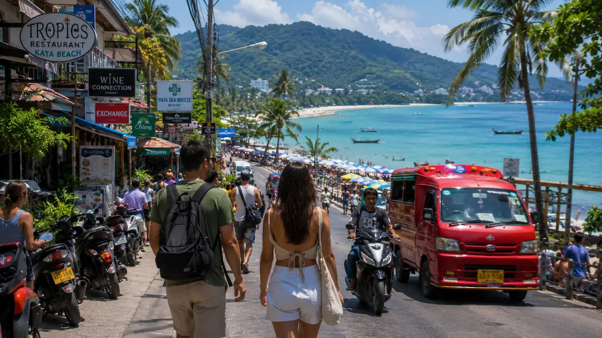 Tourists walking through a busy Phuket beach town beside the coastline in Thailand