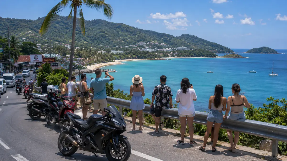 Tourists photographing a Phuket coastal viewpoint beside busy roadside traffic in Thailand