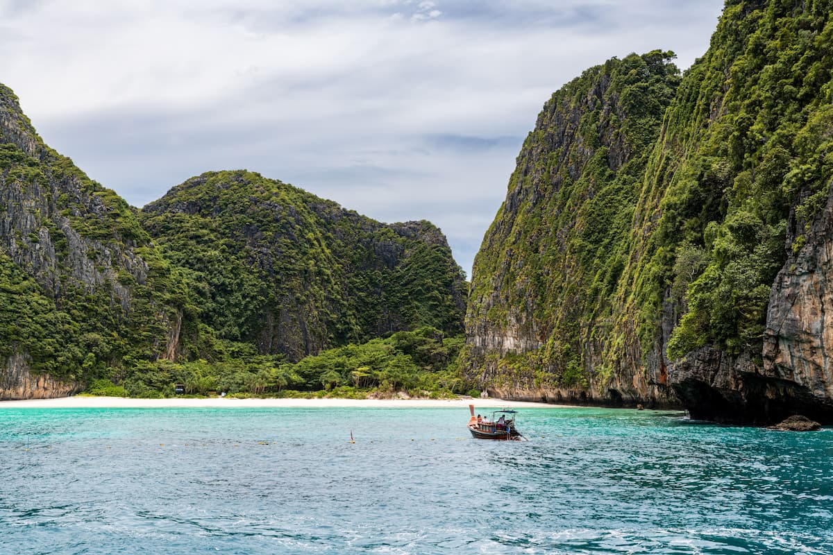 Phi Phi Islands, Thailand – longtail boat beneath towering limestone cliffs and tropical coastline