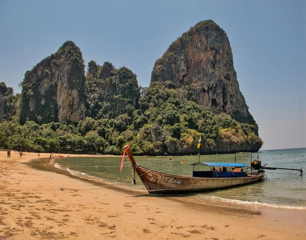 Southern Thailand – longtail boat beneath limestone cliffs at Railay Beach, Krabi
